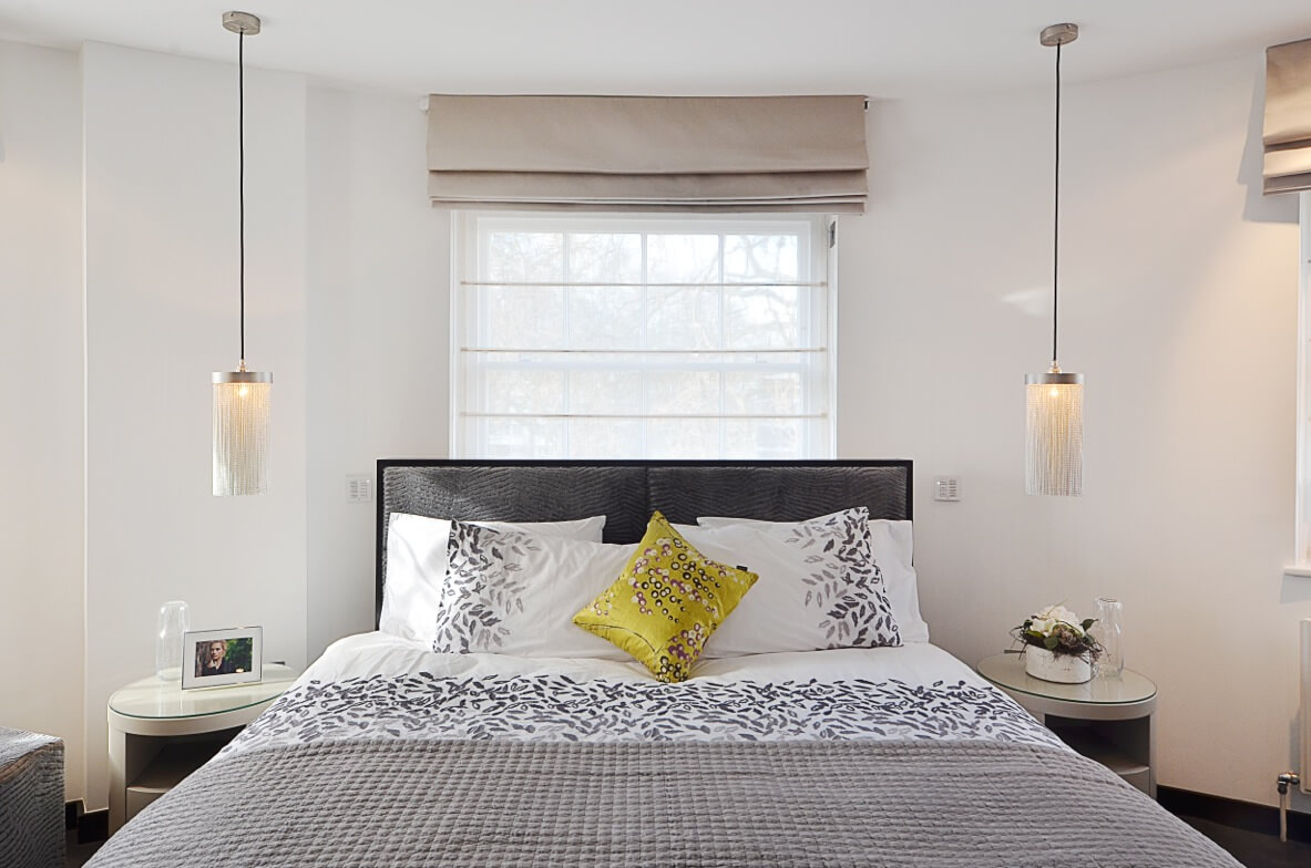 Roman blind with sheer panel above a bed